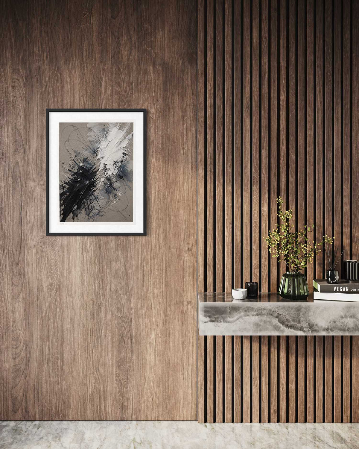 A framed abstract art print with black, white, and gray brushstrokes hangs on a dark wood-paneled wall next to a slatted wood accent wall with a marble console table and decorative plants.