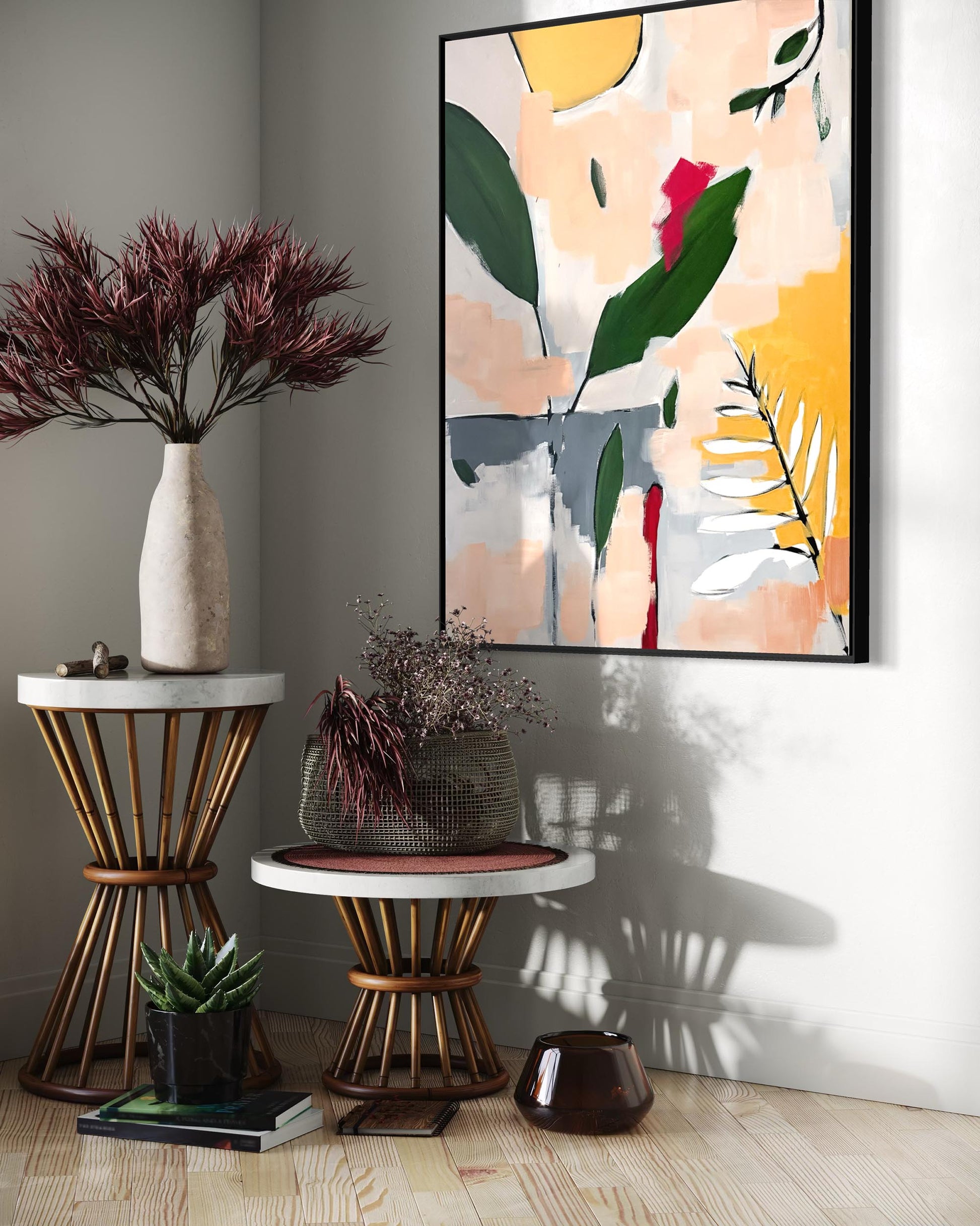 A framed abstract botanical art print hangs on a light gray wall in a styled interior corner with side tables, a vase of dark burgundy foliage, a small succulent, and a dark glass vase.
