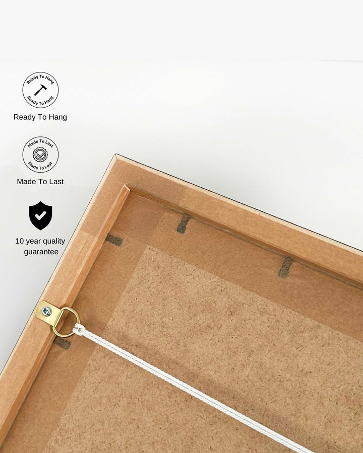 Back of a wooden picture frame with hanging hardware on a white background