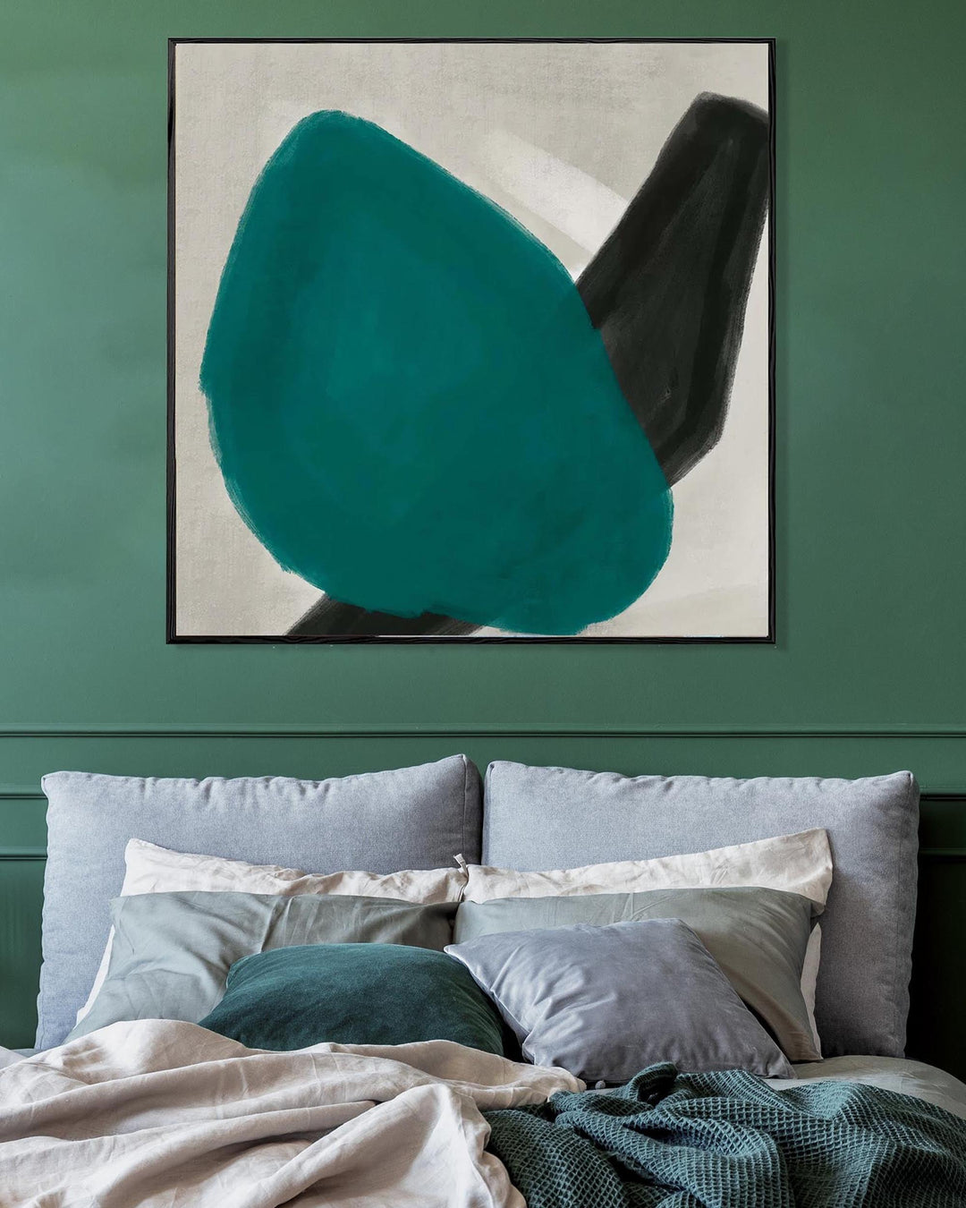 Abstract art piece on a green wall above a bed with pillows.