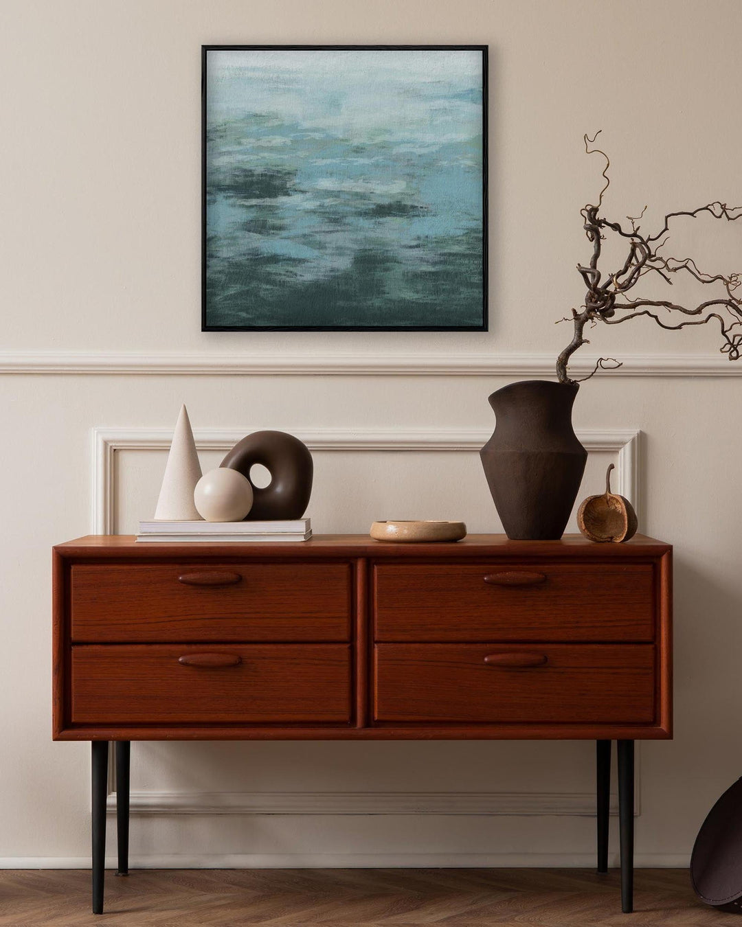 Wooden dresser with decorative items in a room with a painting on the wall.