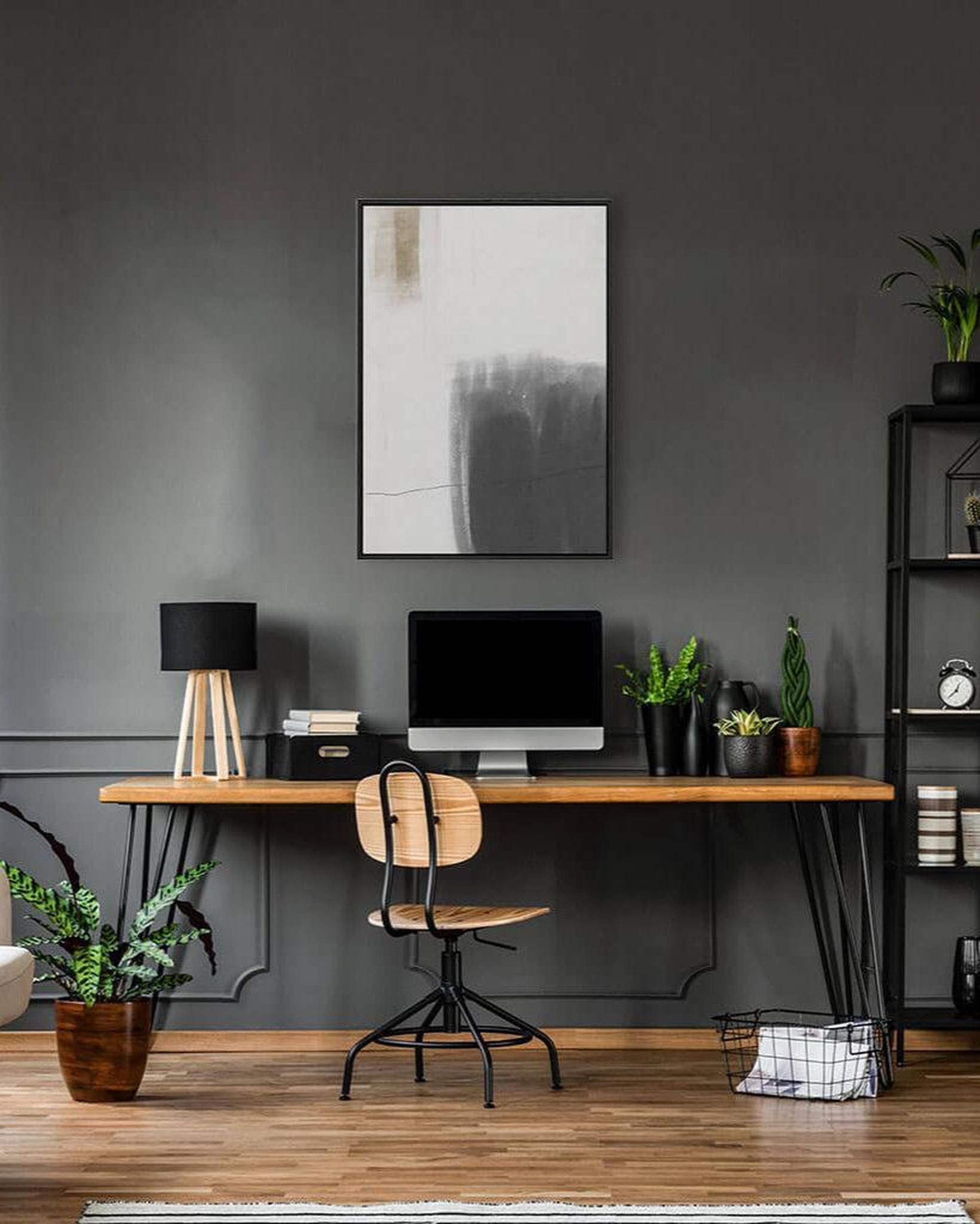 Modern home office with a wooden desk, chair, and decorative elements against a gray wall.