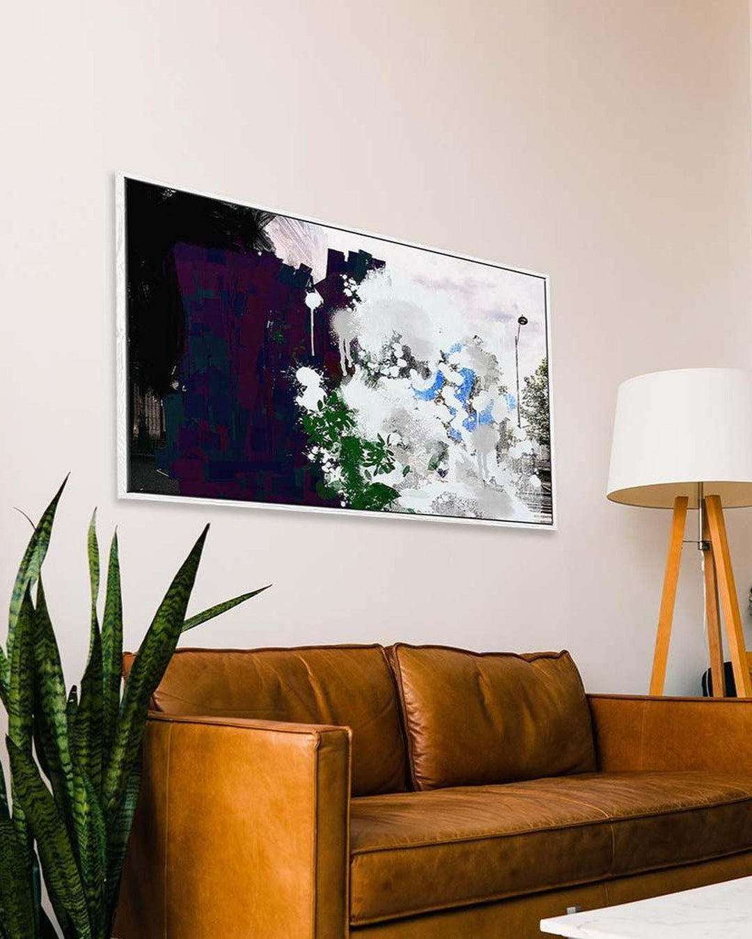 Abstract painting on a wall above a brown leather sofa in a living room.