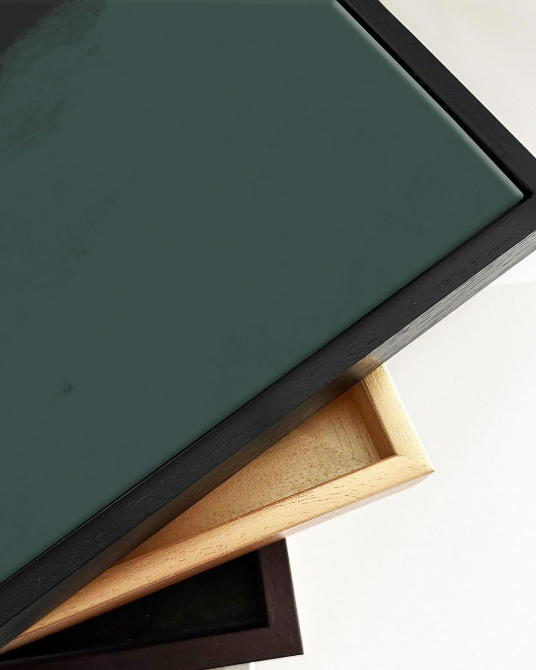 Close-up of a dark green painting with a wooden frame on a white background