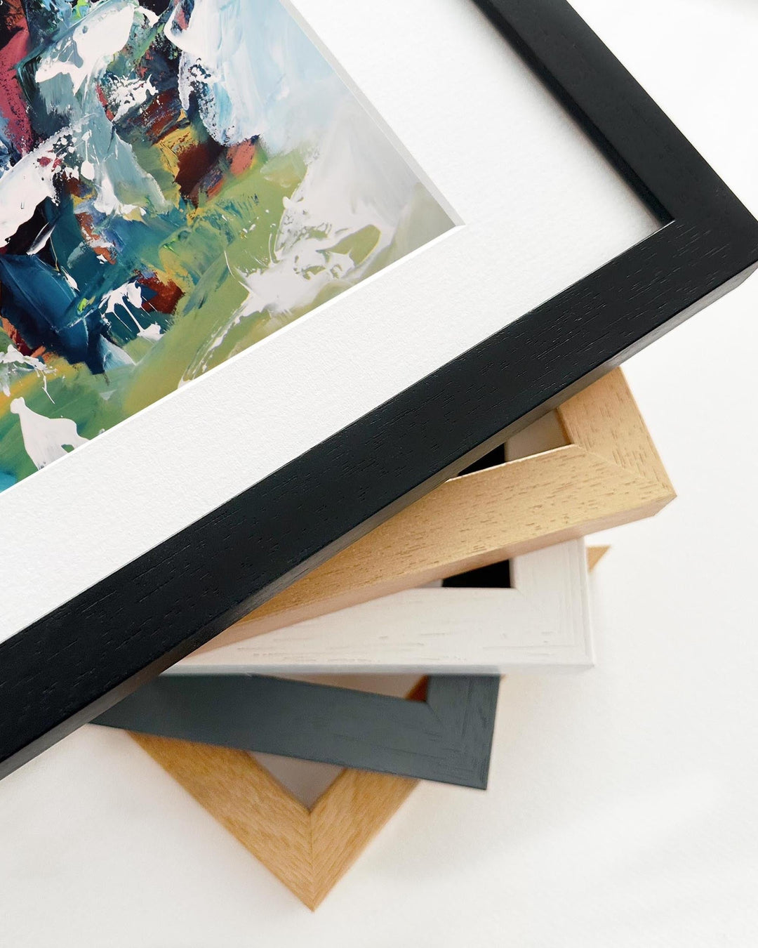 Close-up of various picture frames with a painting in the background