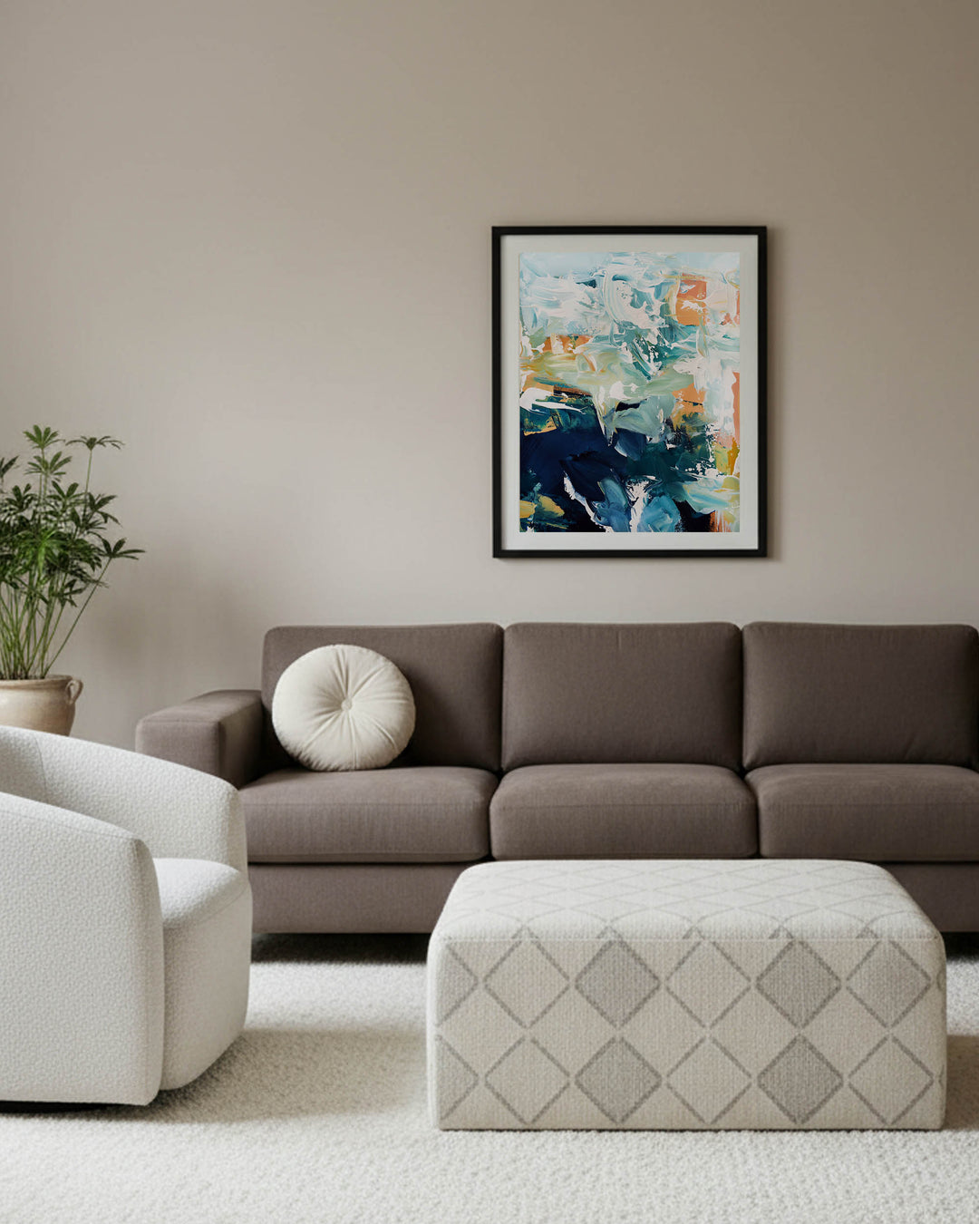 Living room with a brown sofa, white armchair, and abstract art on the wall.