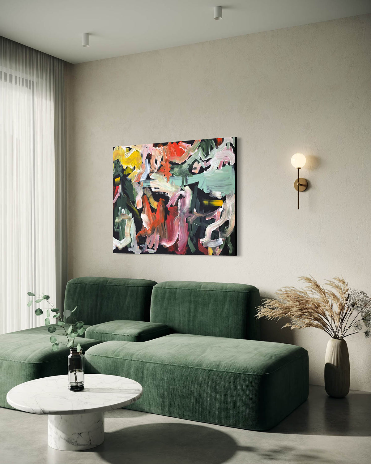 An abstract multicolor canvas painting hangs on a beige wall above a green sectional sofa in a modern living room setting.