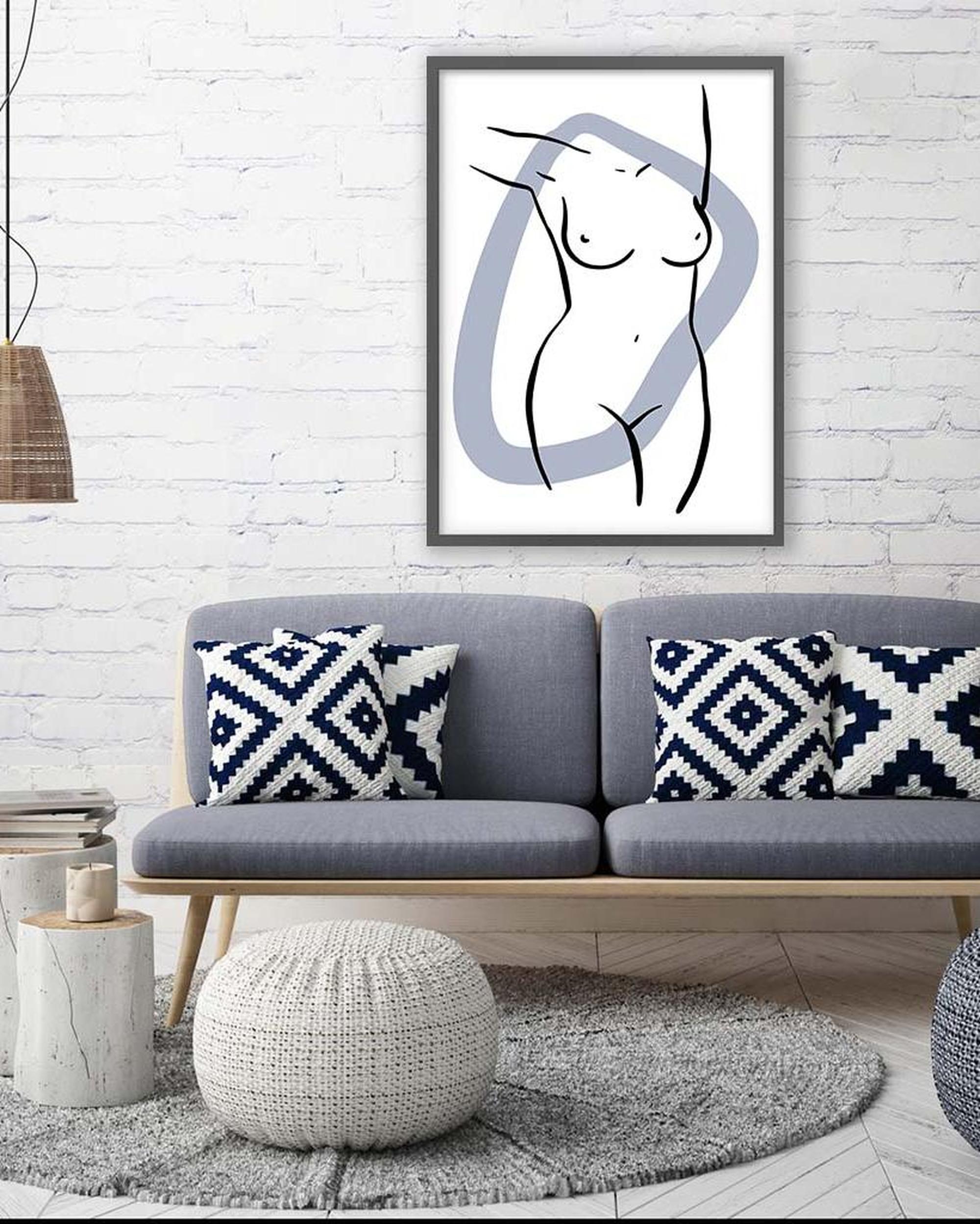 Framed abstract art piece above a gray sofa with patterned cushions in a living room setting.