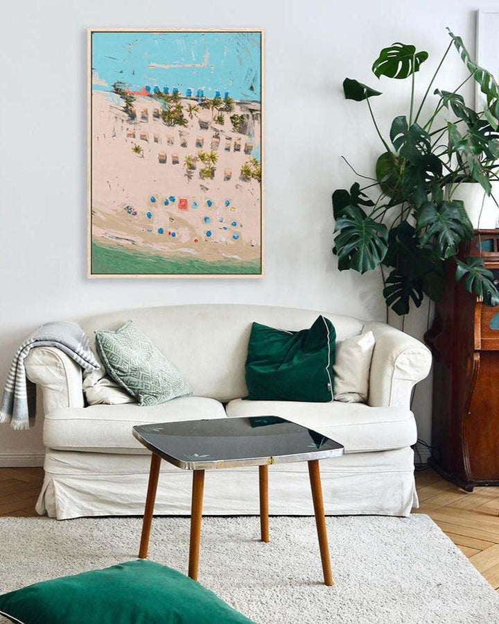 Living room with a white sofa, green cushions, and a framed artwork on the wall.