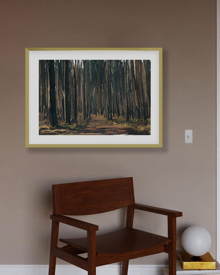 Framed artwork of a forest scene on a wall above a wooden chair.