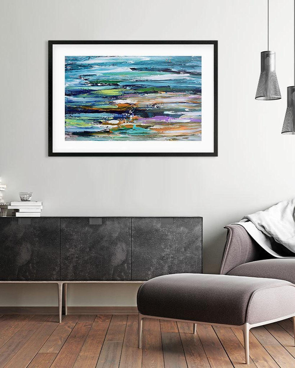 Framed abstract artwork featuring geometric patterns with shades of blue, green, white, and purple, displayed on a wall above a modern gray sofa.