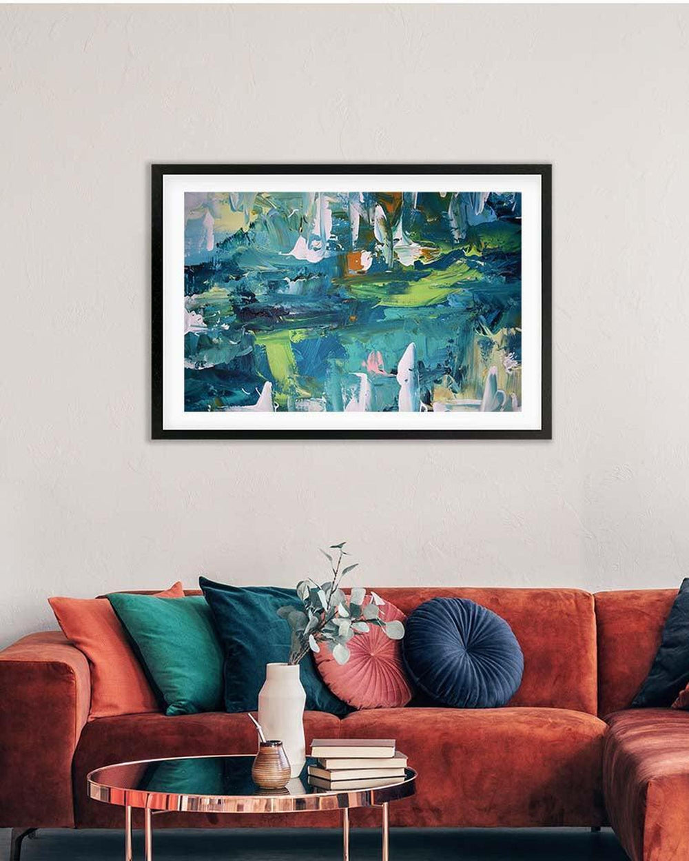 Framed abstract painting on a wall above a red sofa with colorful cushions.