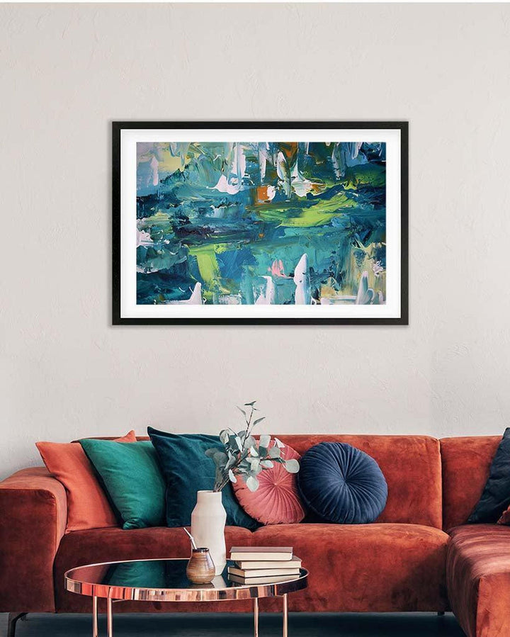 Framed abstract painting on a wall above a red sofa with colorful cushions.