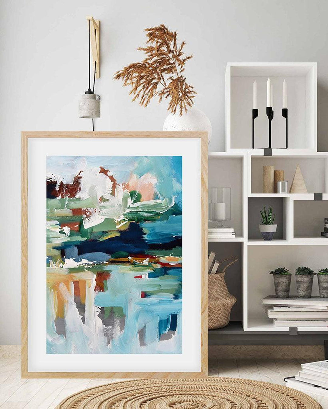 Framed abstract art piece on a wall with a bookshelf in the background