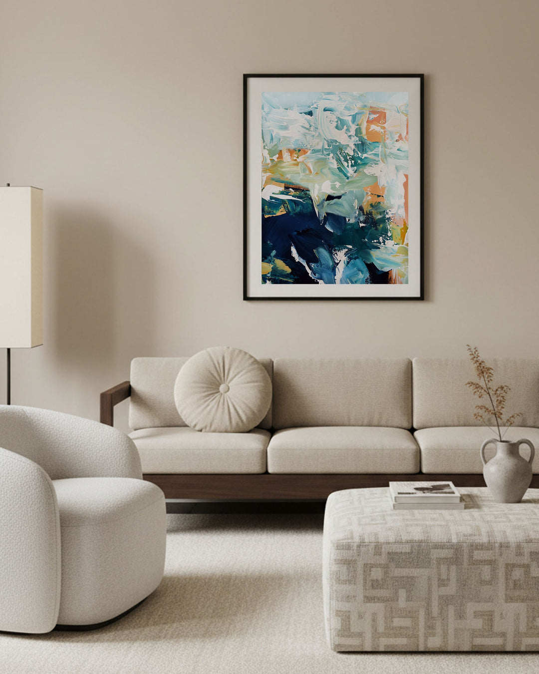 Modern living room with a beige sofa, armchair, and abstract painting on the wall.