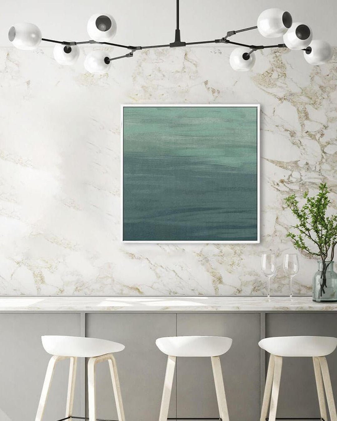 Modern kitchen with marble wall, framed artwork, and white stools.