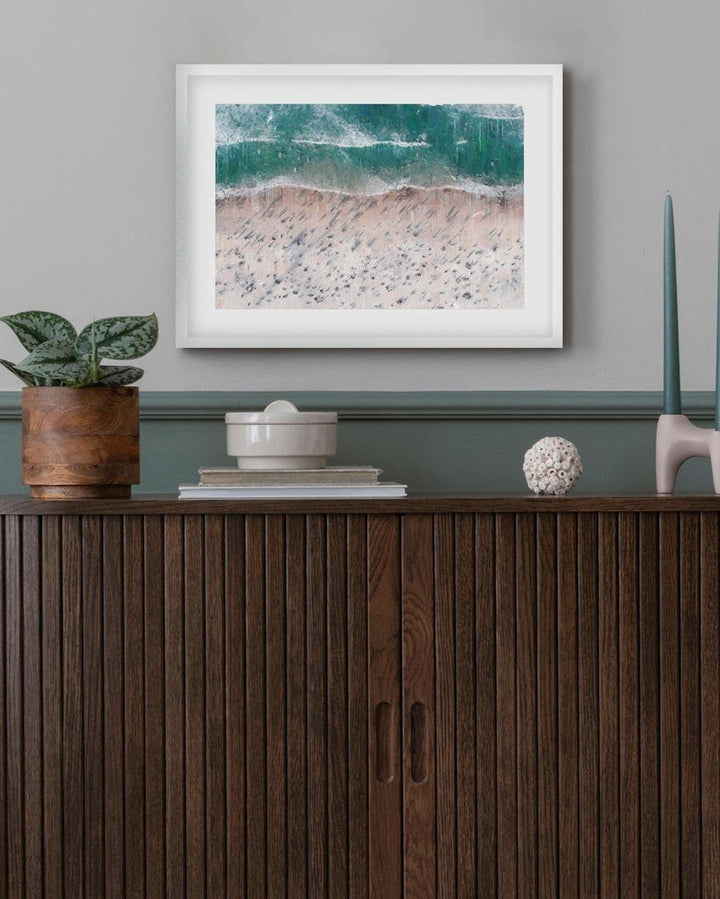 Framed artwork above a wooden cabinet with decorative items