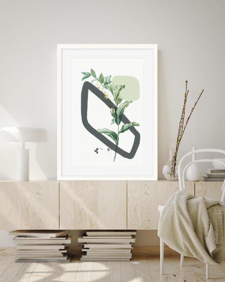 Framed abstract art with green leaves on a wall in a modern interior setting.
