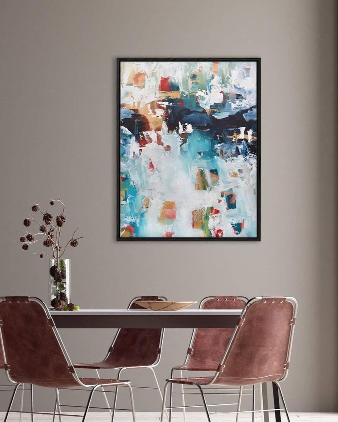 Abstract painting on a wall above a dining table with chairs