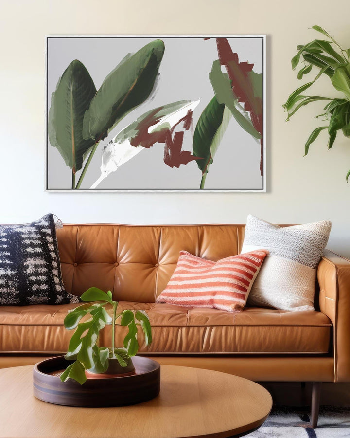Living room with a brown leather sofa, colorful pillows, and a plant on a coffee table.
