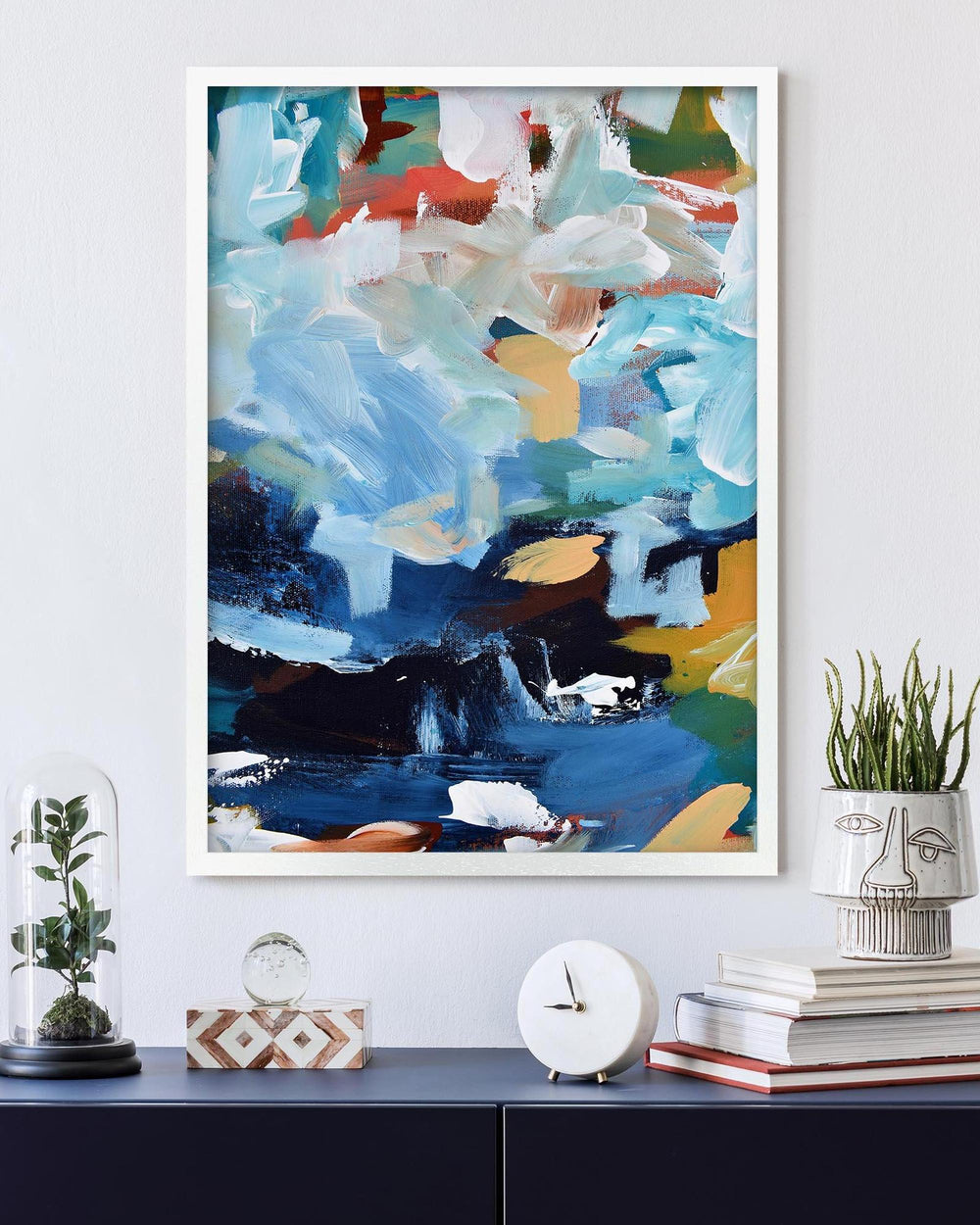 Abstract painting on a wall above a shelf with decorative items.