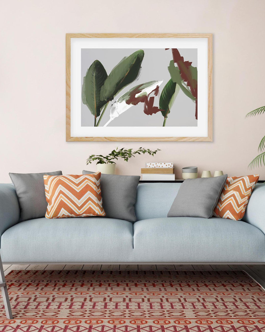 Living room with a light blue sofa, gray and orange patterned cushions, and a framed botanical print on the wall.