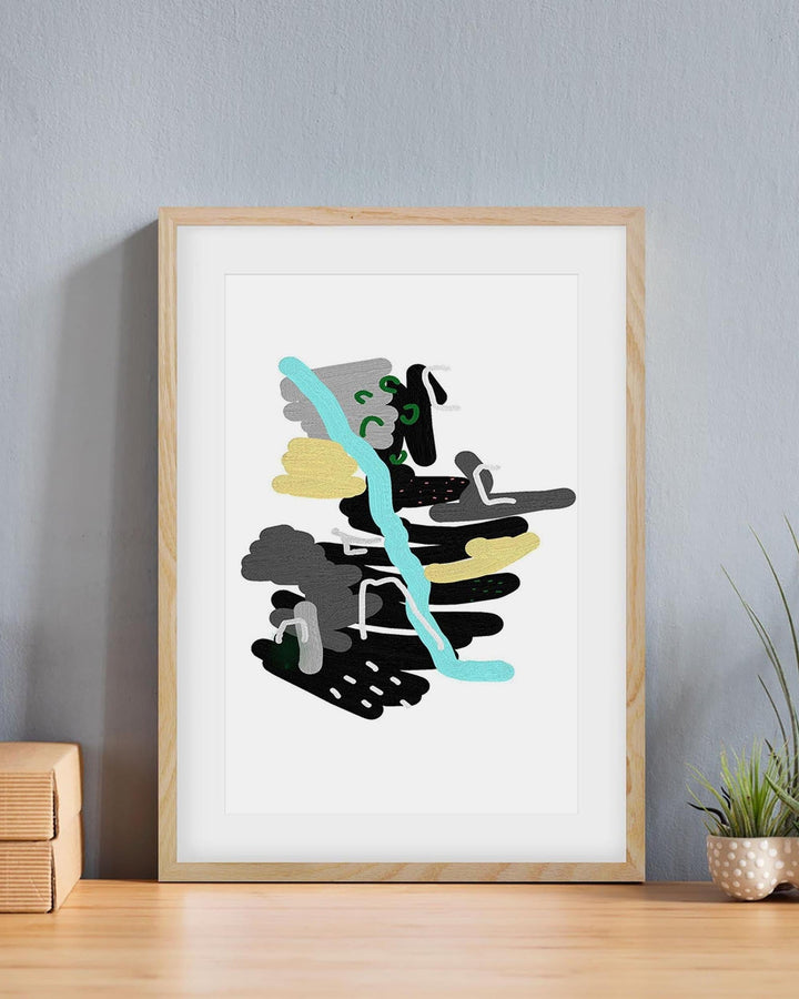 Framed abstract art print on a wall with a plant and wooden box in the background