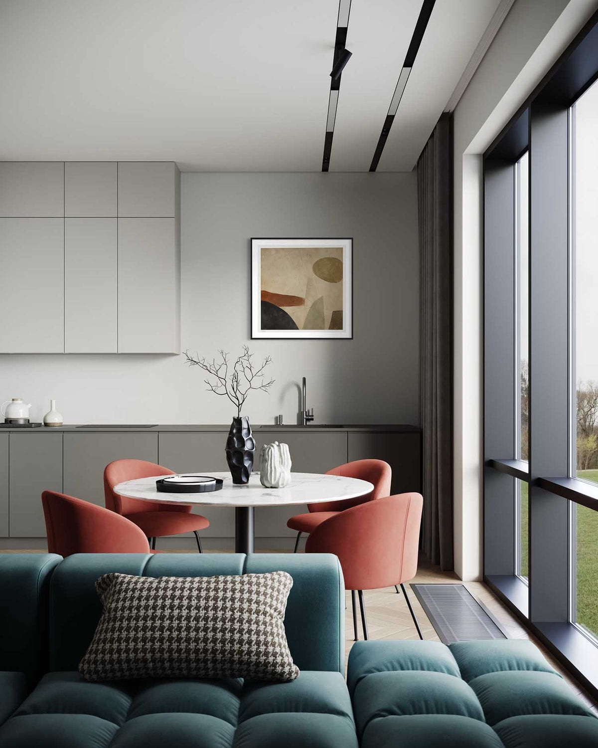 A modern interior scene showing a teal tufted sofa in the foreground, a round dining table with coral chairs, a gray kitchen cabinetry wall, and a large window with dark gray framing. No person or animal is present, but this is still not a clean isolated product shot; it is a real room environment, so subject_type is Lifestyle.