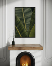 Framed leaf print above a fireplace with a wooden mantel.