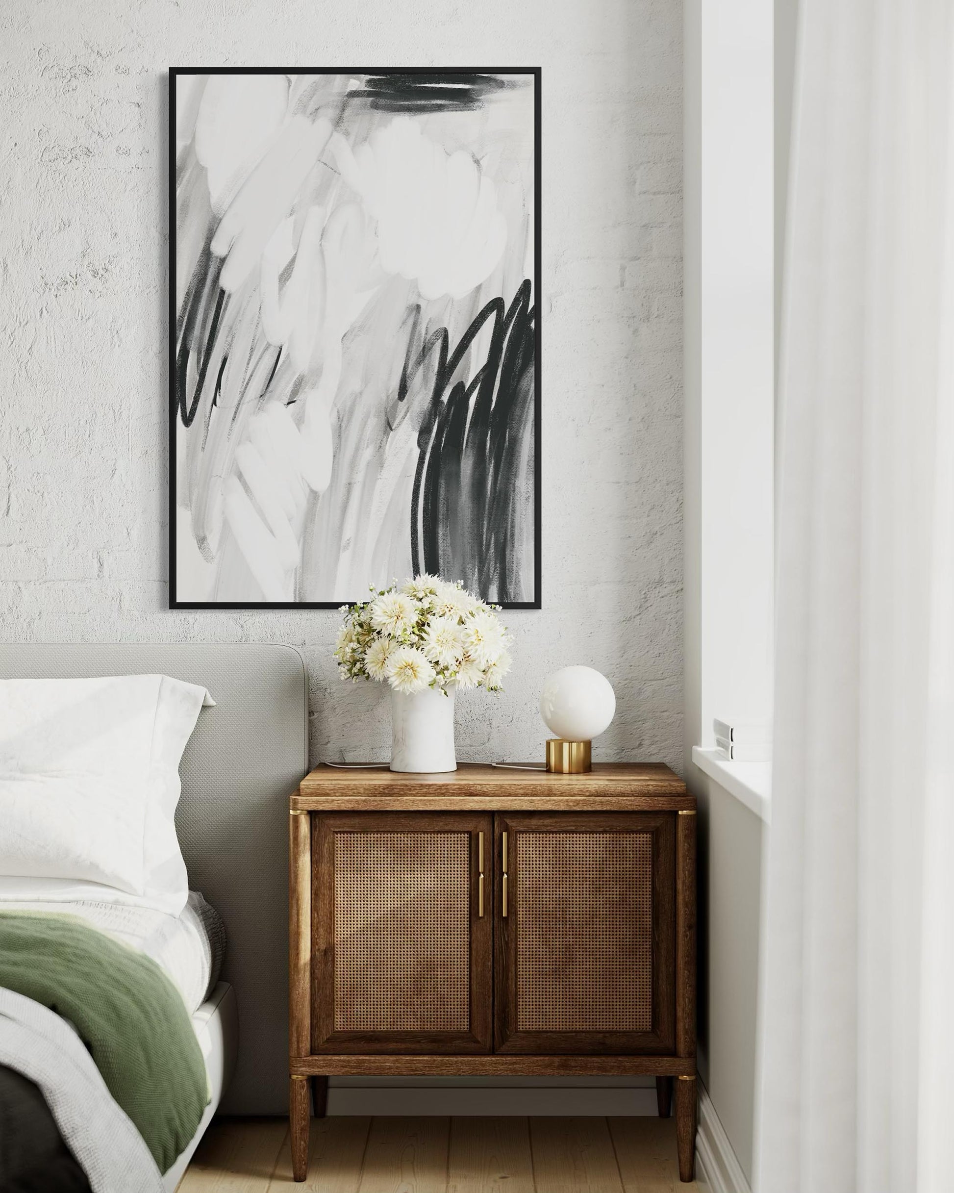 Modern bedroom with abstract art, wooden side table, and white flowers.