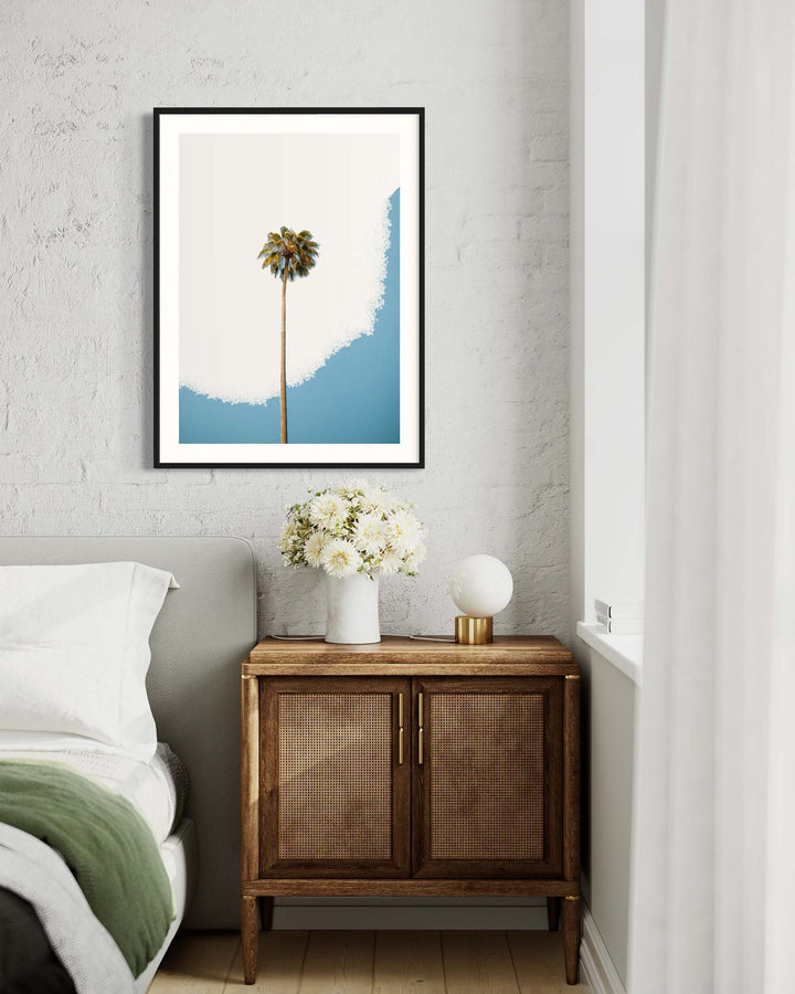 Framed artwork of a palm tree against a blue sky in a bedroom setting.