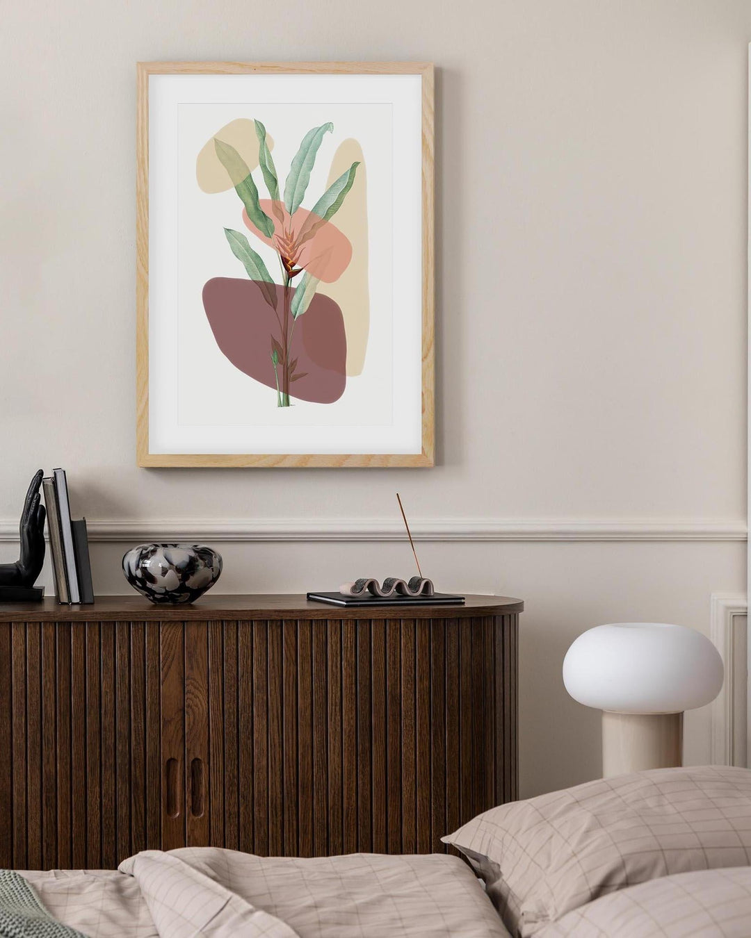 Framed abstract art piece on a wall above a wooden cabinet.