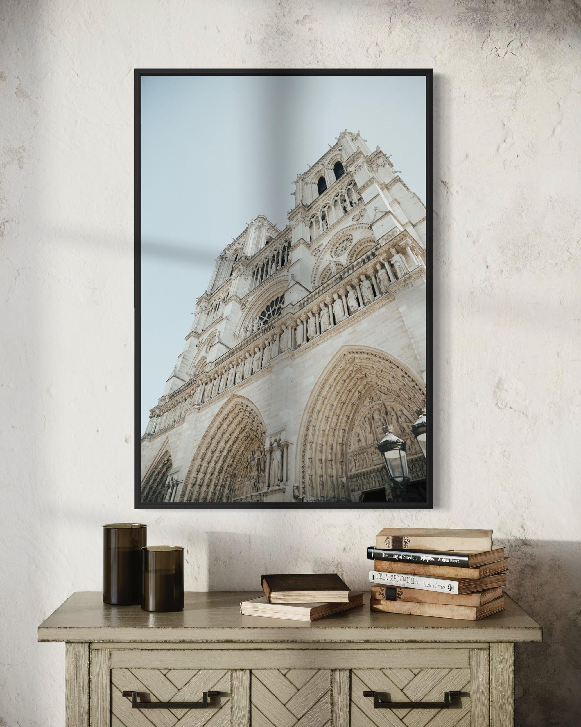 Framed photograph of a cathedral on a wall above a wooden side table with books.