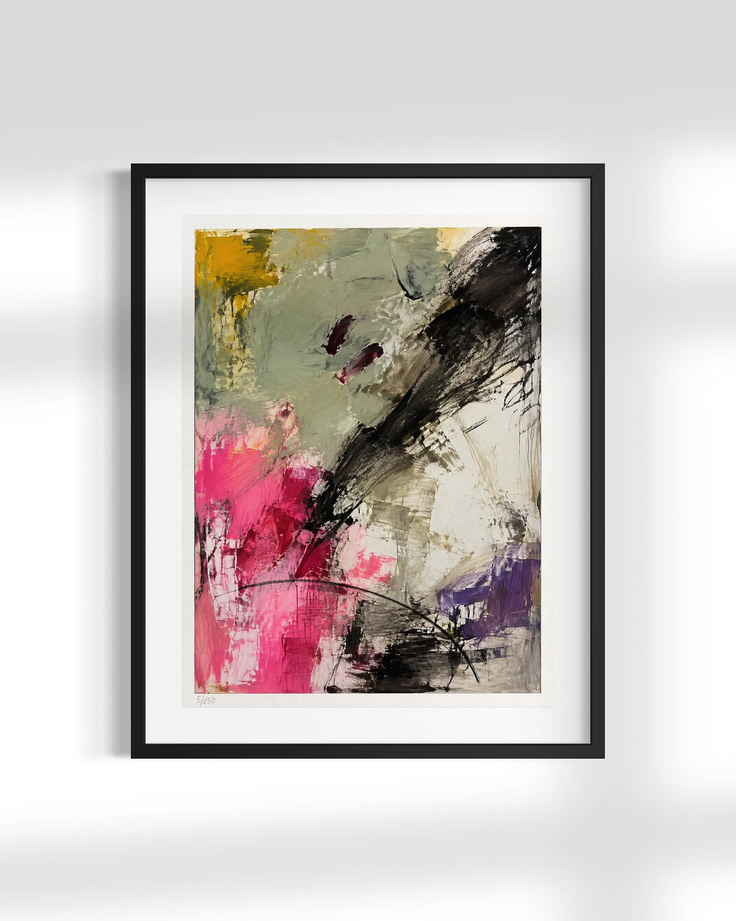 A framed abstract art print featuring expressive brushstrokes in black, pink, yellow, purple, and gray on a white mat, set against a light gray wall with soft shadows.