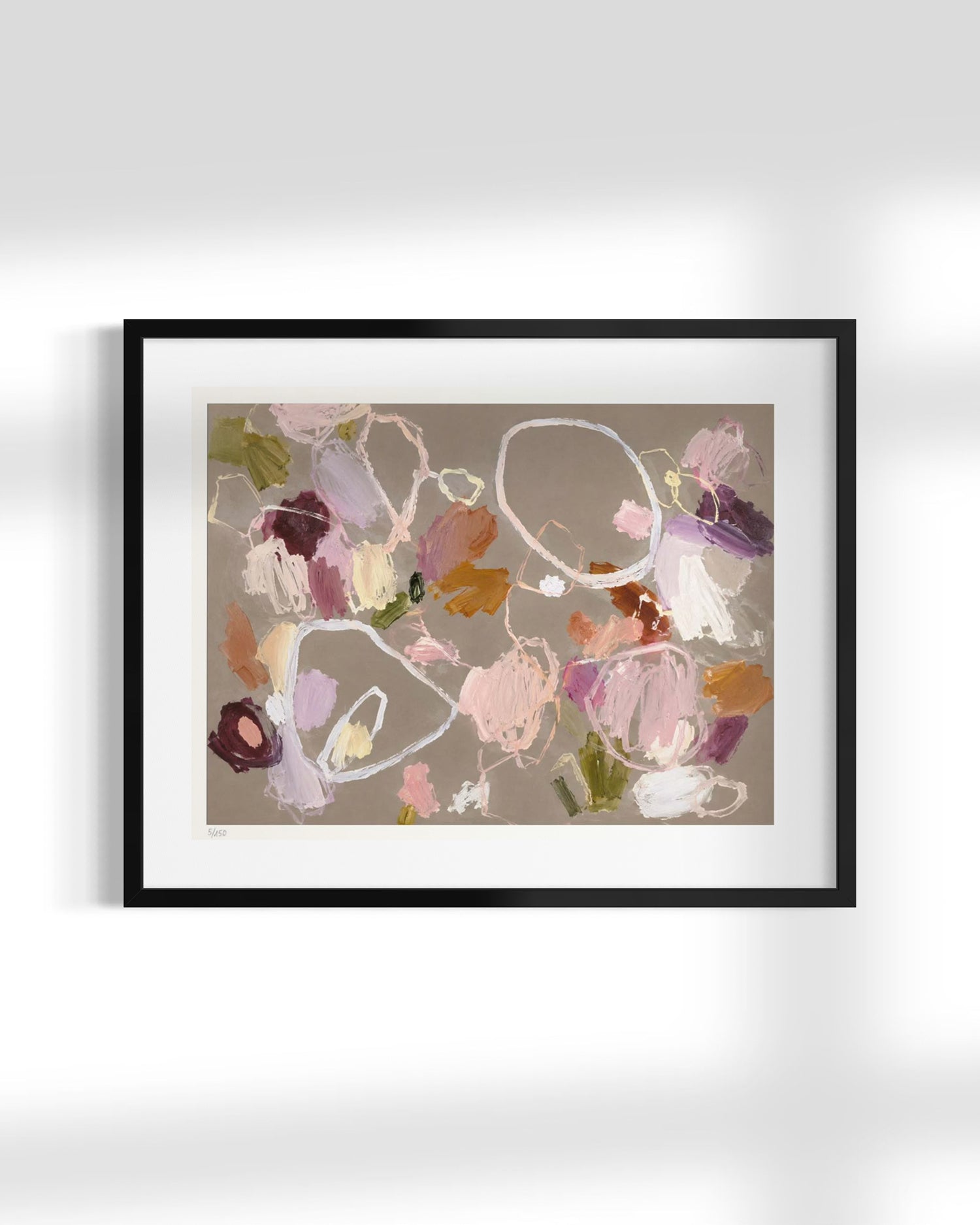 Framed abstract art print featuring fluid, organic brushstrokes in shades of pink, purple, brown, and white on a warm taupe background, presented in a black frame with a white mat against a light gray wall.