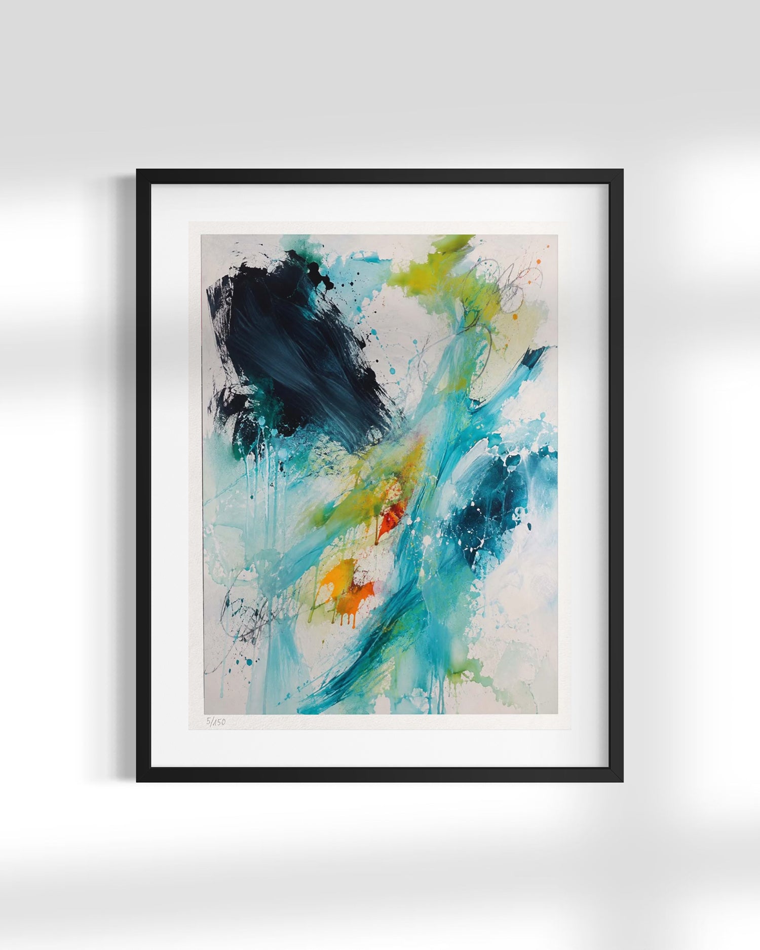 A framed abstract art print featuring expressive brushstrokes and splatters in teal, blue, green, black, orange, and white, presented in a black frame against a light gray wall.