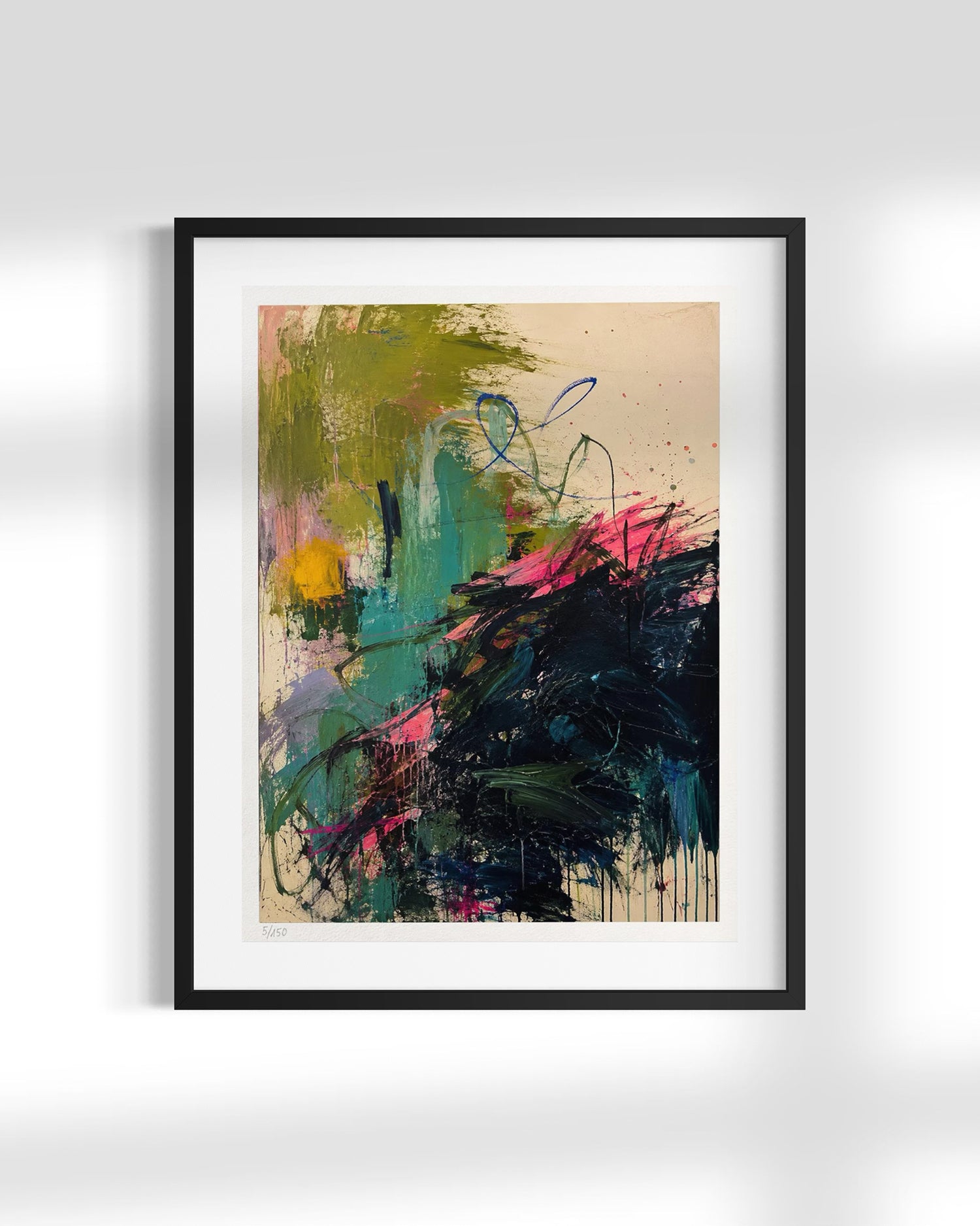 A framed abstract art print featuring expressive brushstrokes in green, teal, black, pink, and yellow on a cream background, presented in a black frame with a white mat against a light gray wall.