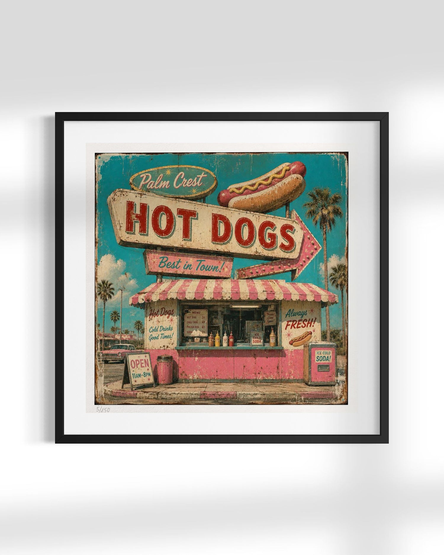 Framed vintage-style wall art featuring a retro hot dog stand with a large sign reading 'Palm Crest Hot Dogs,' a hot dog illustration, and a turquoise sky background, shown in a black frame with white mat against a light gray wall.