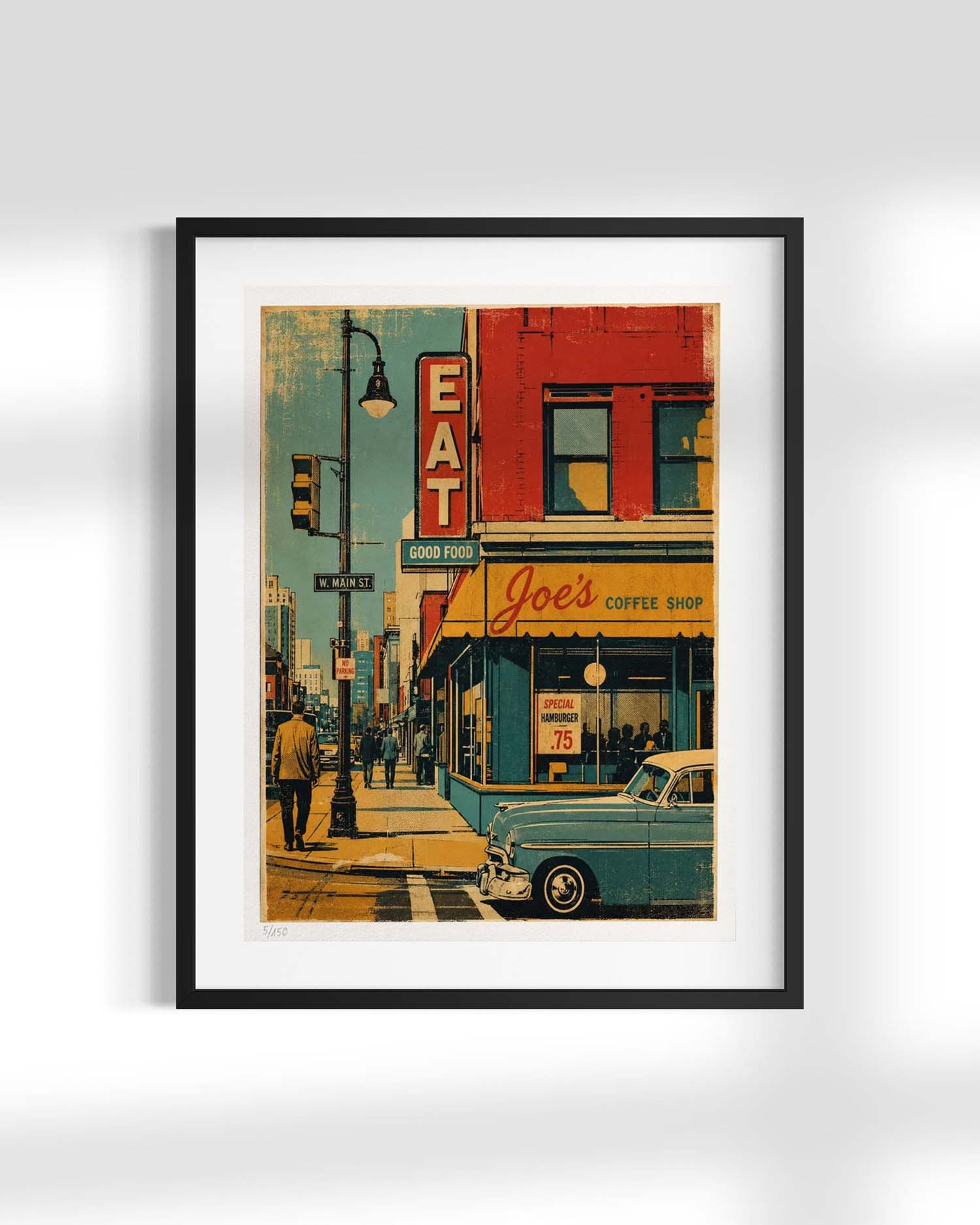 A framed vintage-style city street art print hangs on a light gray wall. The artwork depicts a retro scene with a red building, a blue car, pedestrians, and storefront signage, including a prominent vertical 'EAT' sign and a coffee shop sign reading 'Joel's Coffee Shop.