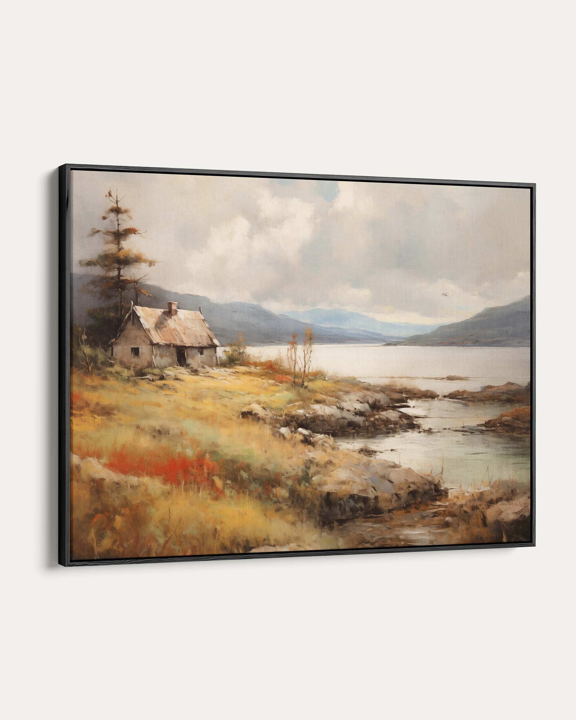 Framed painting of a lakeside cabin with mountains in the background