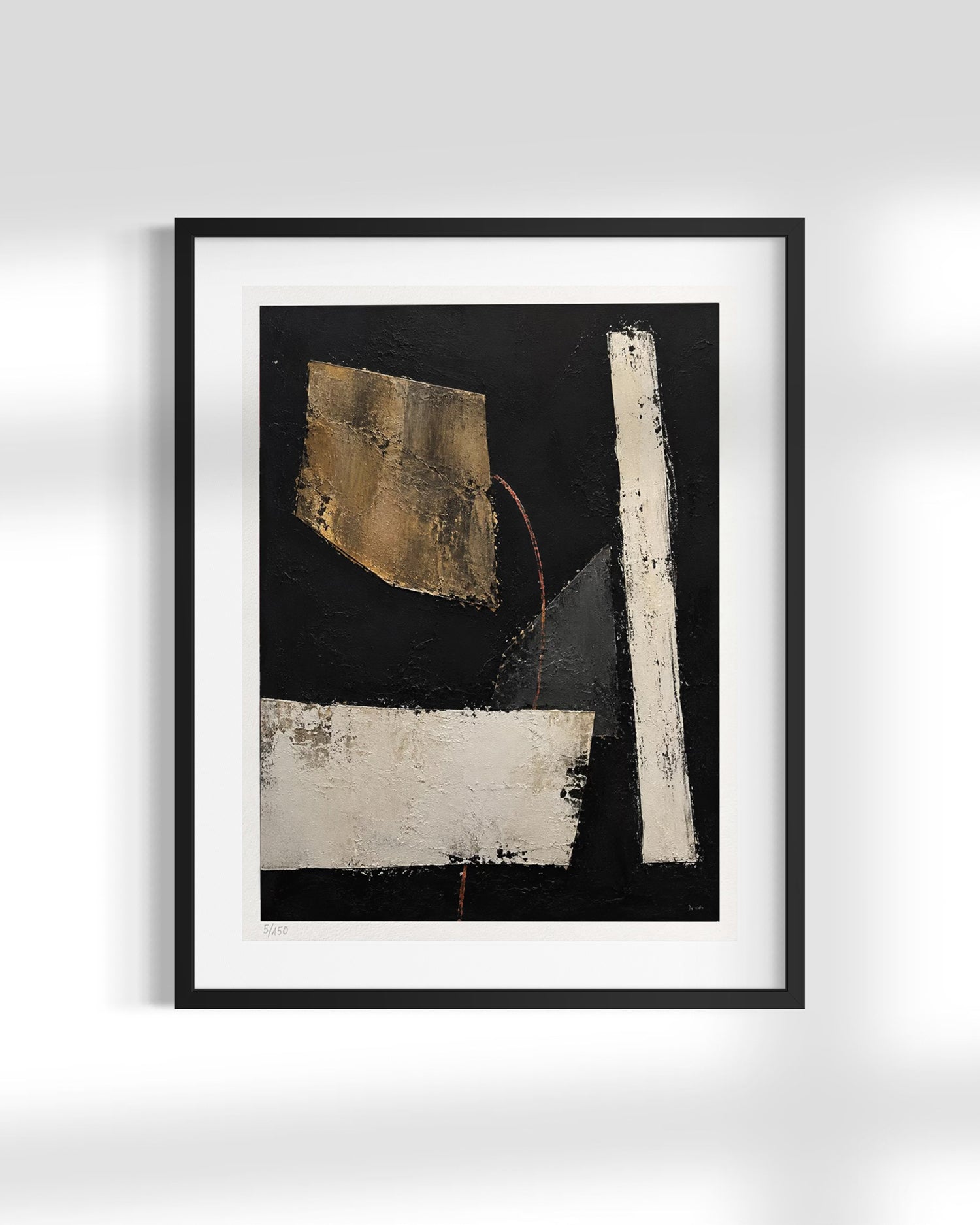 A framed abstract art print featuring a black background with textured white and gold geometric shapes, presented in a black frame with a white mat against a light gray wall.
