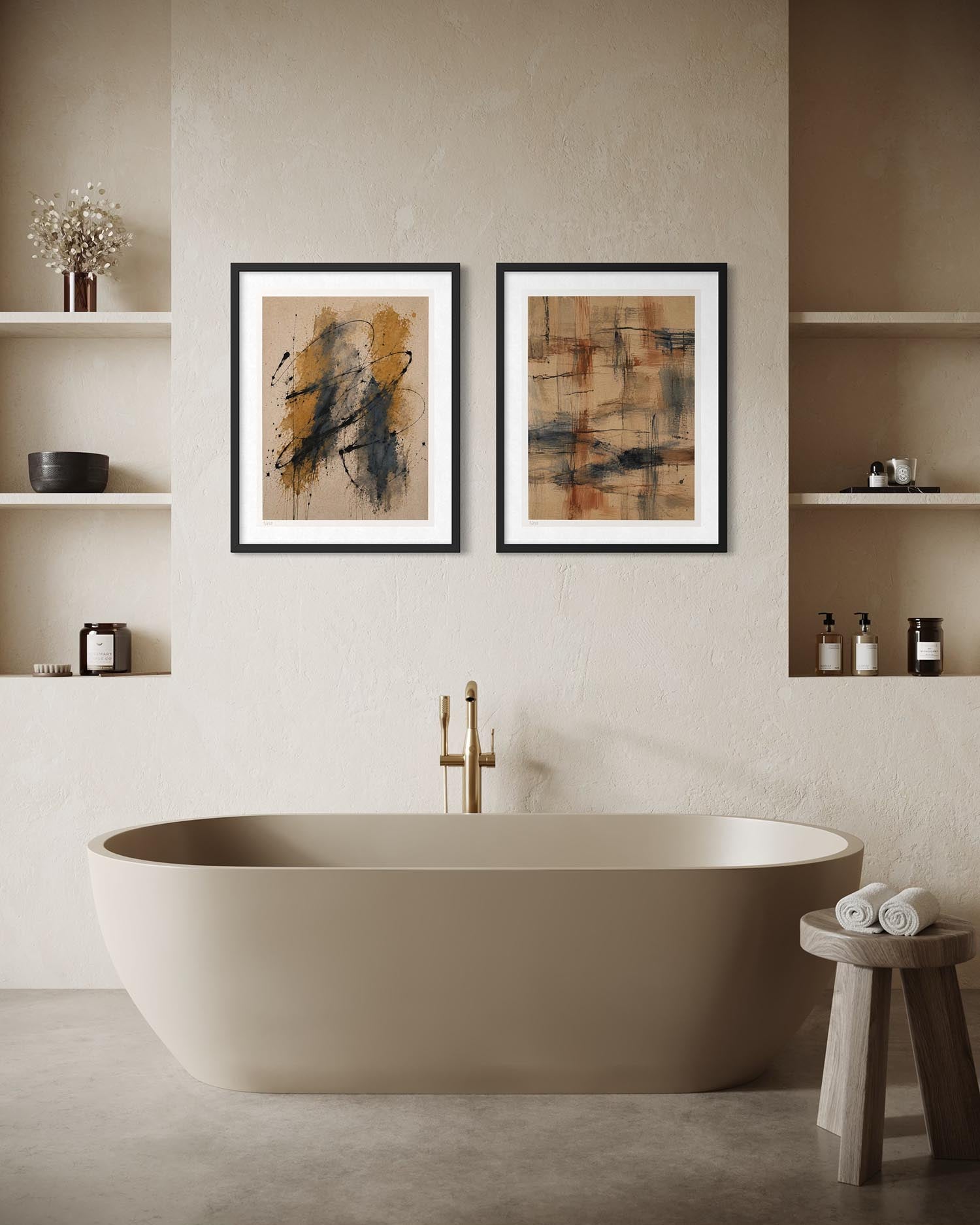 Two framed abstract art prints with black, gold, and brown tones hang on a textured beige wall above a freestanding beige bathtub in a modern bathroom setting.