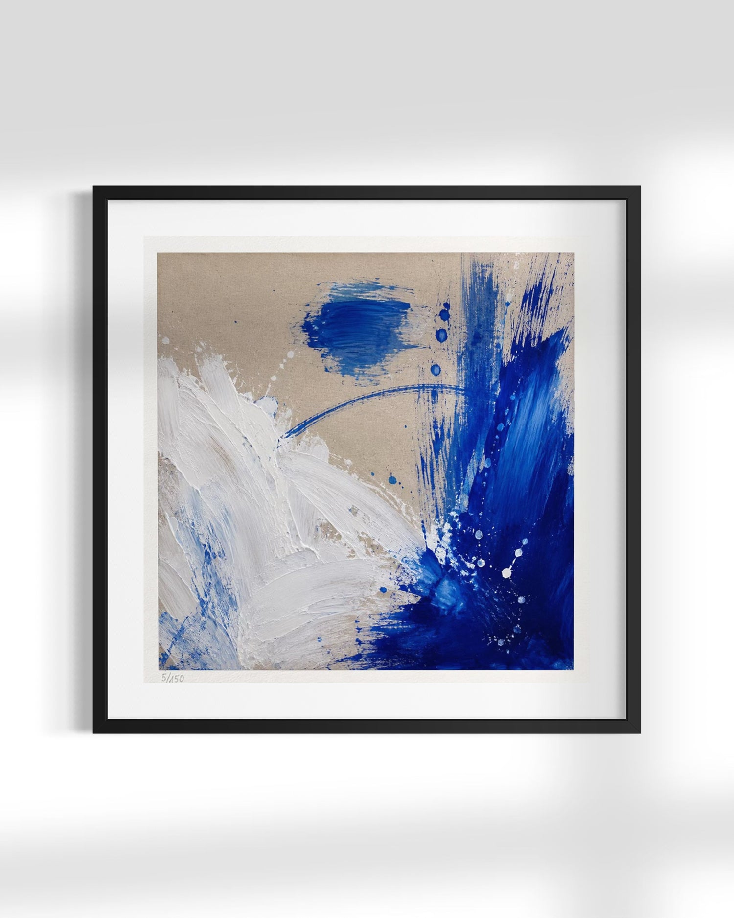Framed abstract wall art featuring bold blue and white paint strokes on a warm beige background, presented in a black frame with a white mat against a light gray wall.