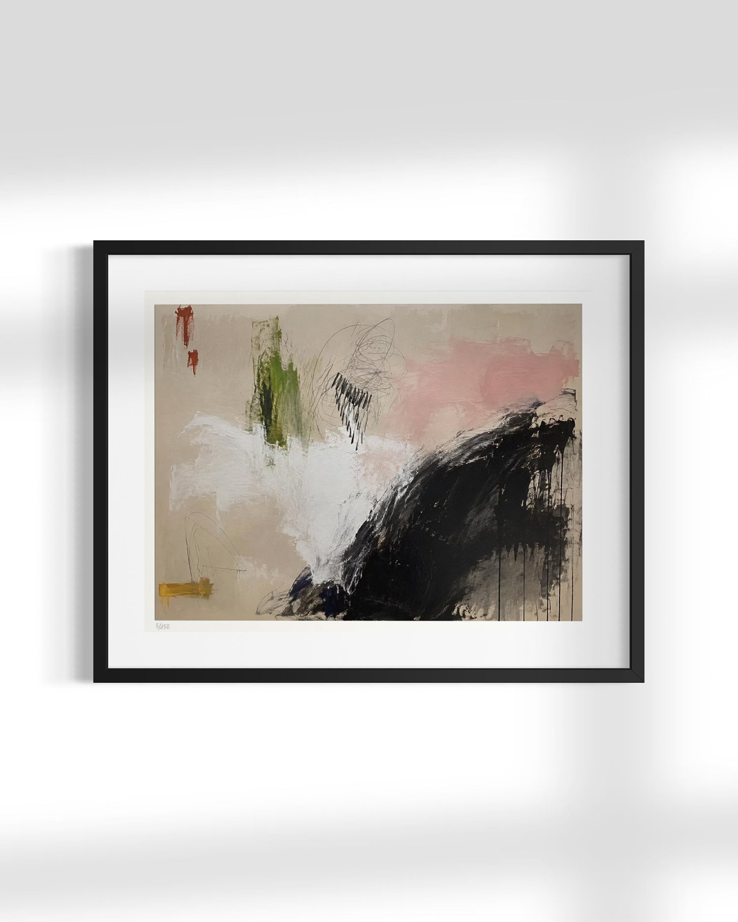 A framed abstract art print featuring expressive brushstrokes in black, white, beige, pink, green, and small red accents, displayed against a light gray wall.