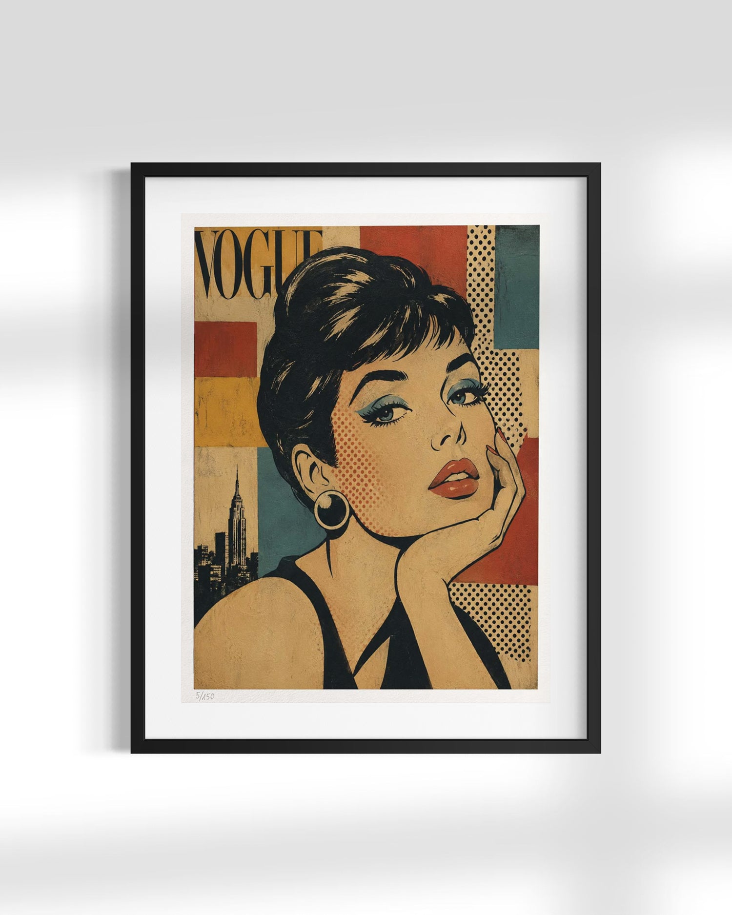 A framed pop-art style poster featuring a stylized portrait of Audrey Hepburn with the word 'VOGUE' in the background, shown hanging on a light gray wall.