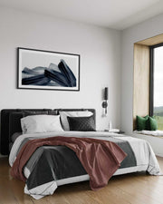 Modern bedroom with a bed, abstract art on the wall, and a window with greenery.