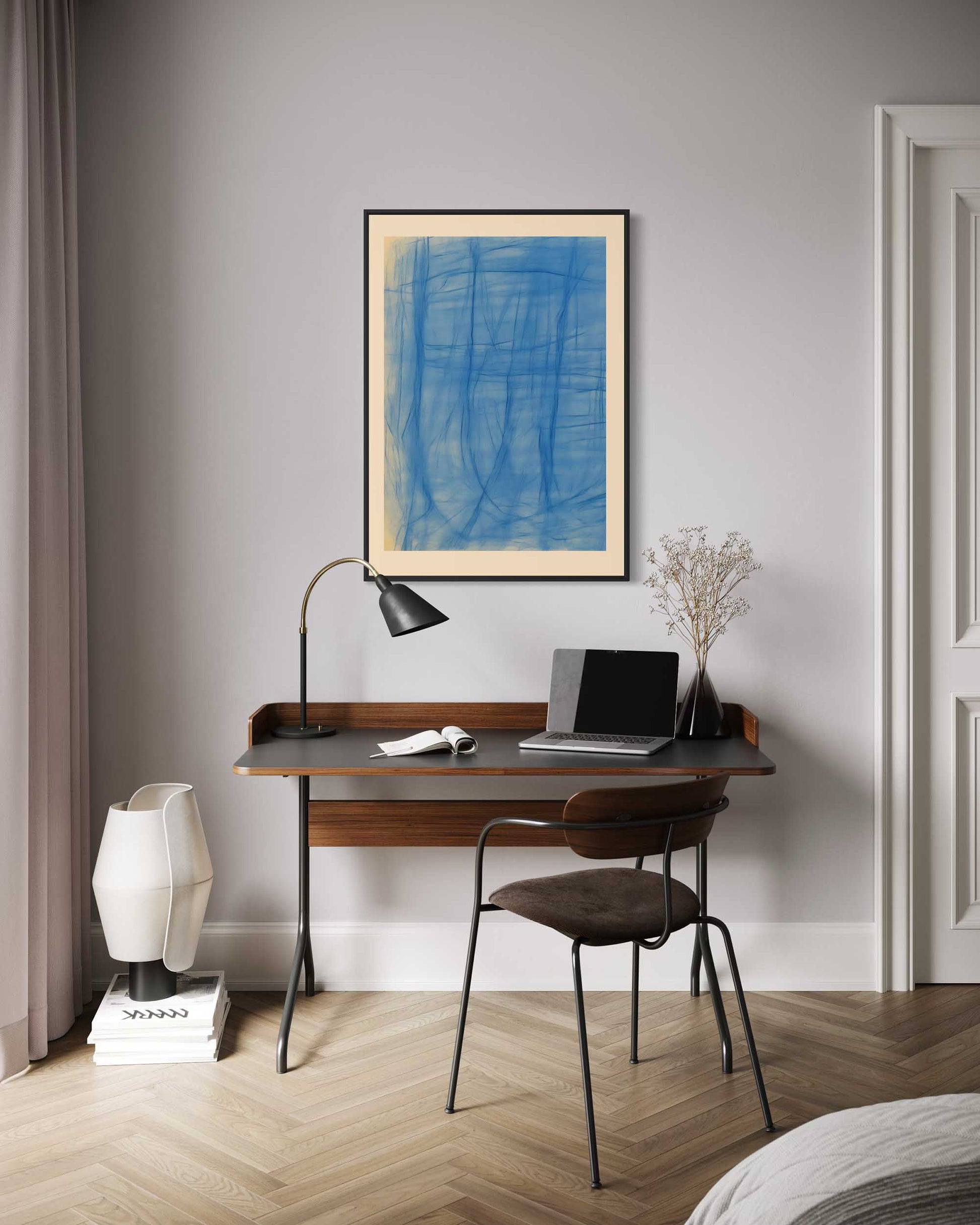 Modern home office with wooden desk, chair, lamp, and abstract art on gray wall.