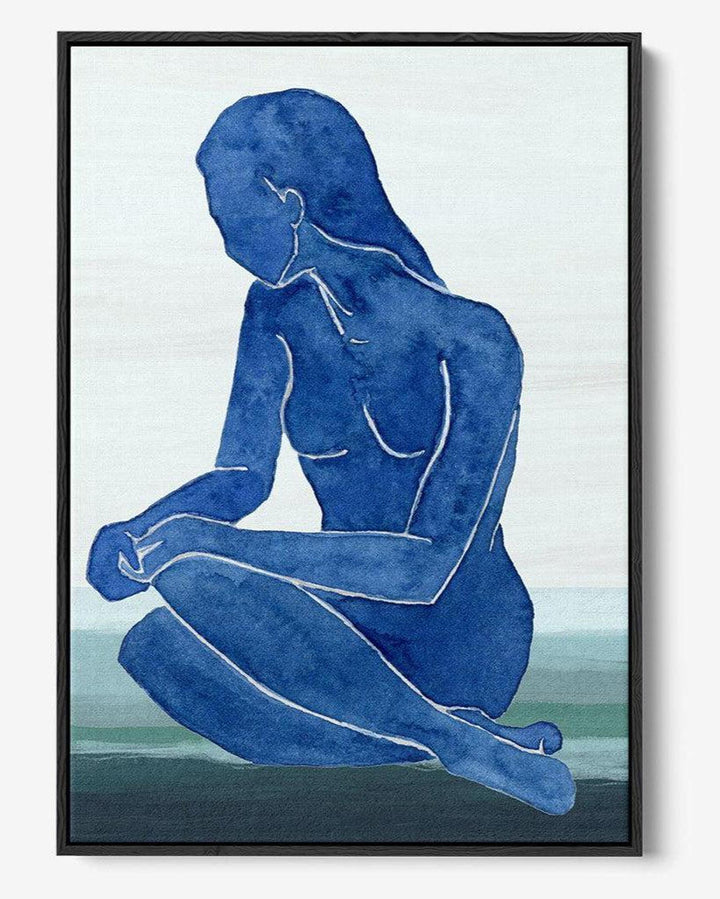 Framed artwork of a blue silhouette of a nude figure sitting on a landscape.
