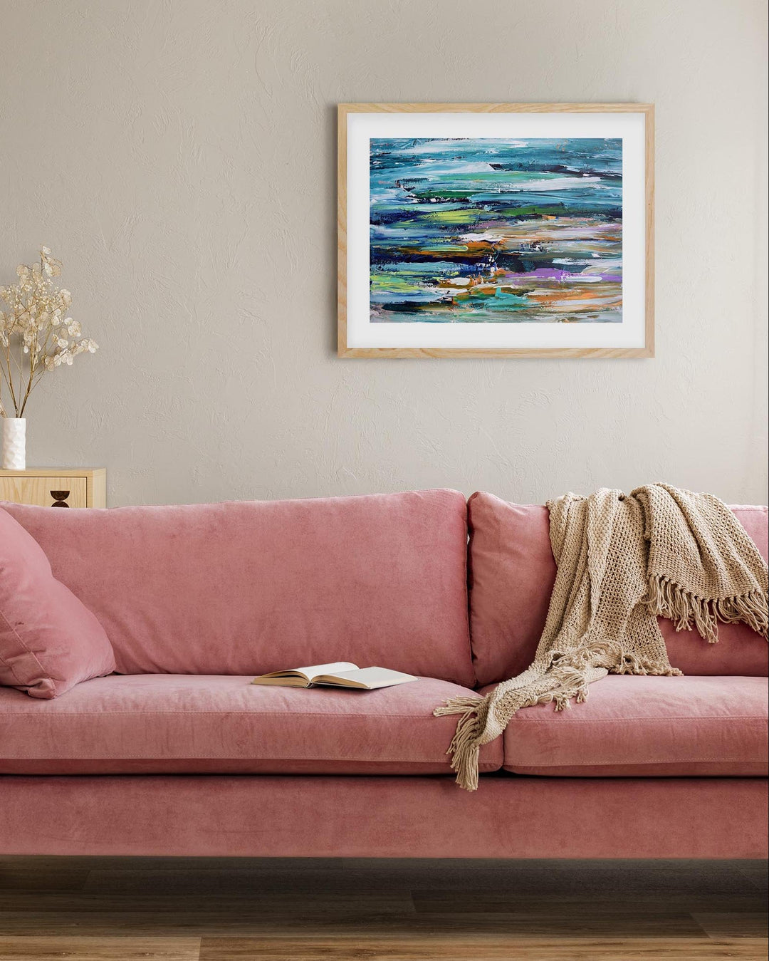 abstract seascape framed print in living room above a pink modern sofa