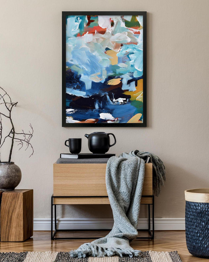 Abstract art piece on a wall above a wooden console table with decorative items.
